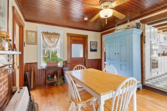 dining space featuring ornamental molding, light wood-type flooring, wooden walls, and wood ceiling