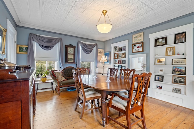 dining space with built in shelves, light hardwood / wood-style floors, and crown molding