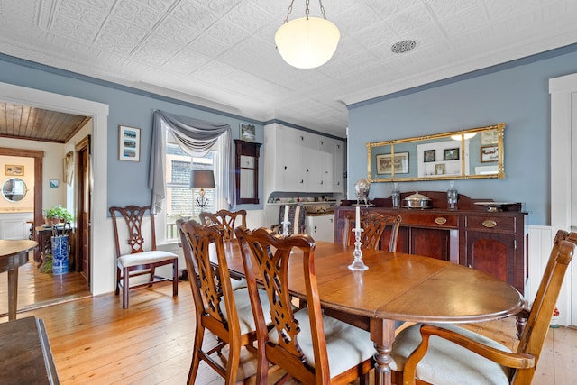 dining room with light hardwood / wood-style floors and crown molding