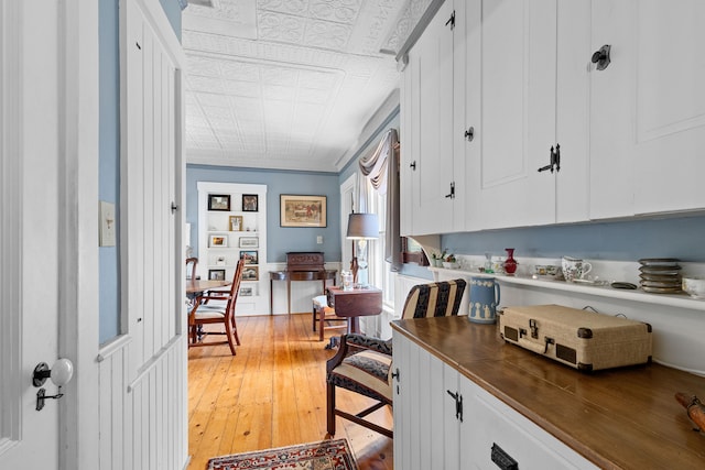 kitchen with light hardwood / wood-style flooring, white cabinetry, and crown molding