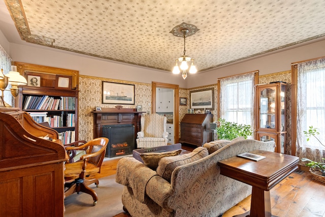 living area with a notable chandelier, light hardwood / wood-style flooring, and plenty of natural light