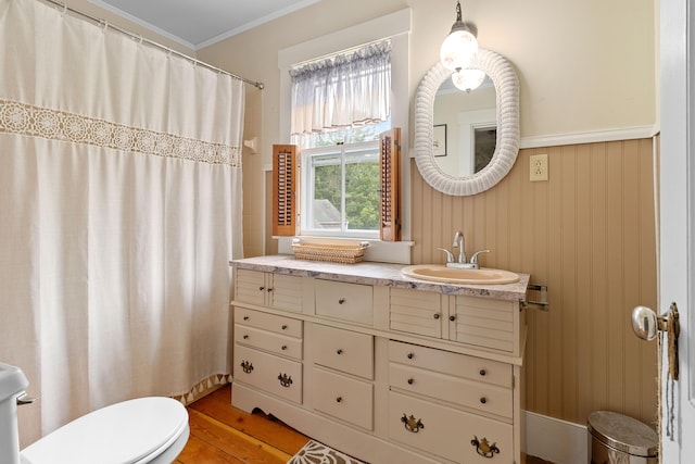 bathroom featuring vanity, wood-type flooring, walk in shower, crown molding, and toilet