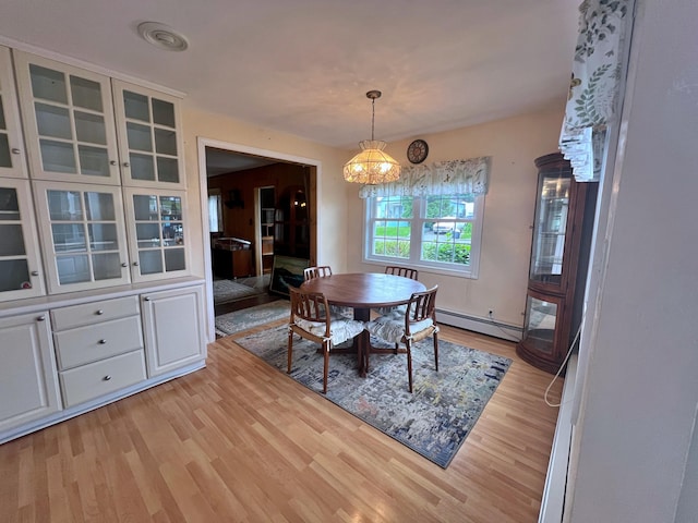 dining space with an inviting chandelier, a baseboard heating unit, and light hardwood / wood-style flooring