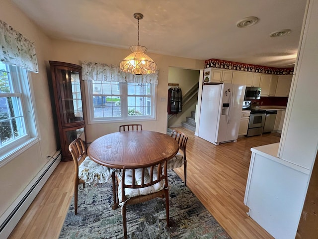 dining area with light wood-type flooring, a baseboard heating unit, and a chandelier