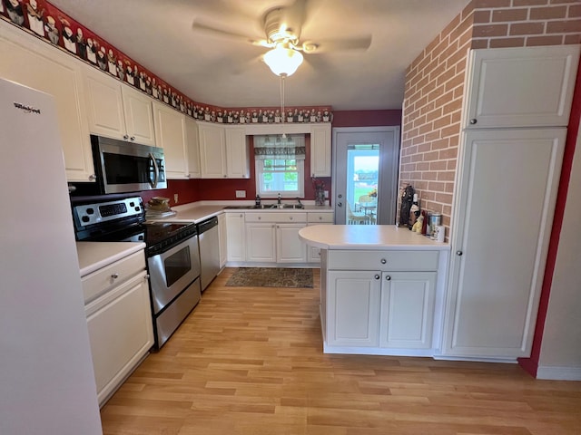 kitchen with light wood-type flooring, ceiling fan, stainless steel appliances, and white cabinets