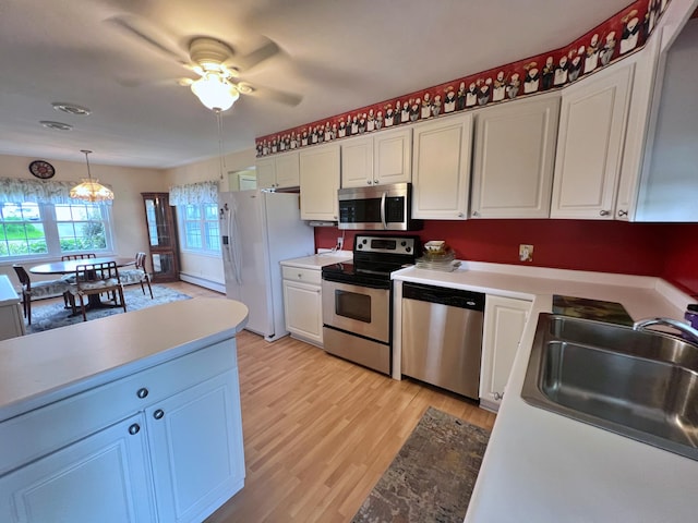 kitchen featuring appliances with stainless steel finishes, ceiling fan with notable chandelier, and white cabinets