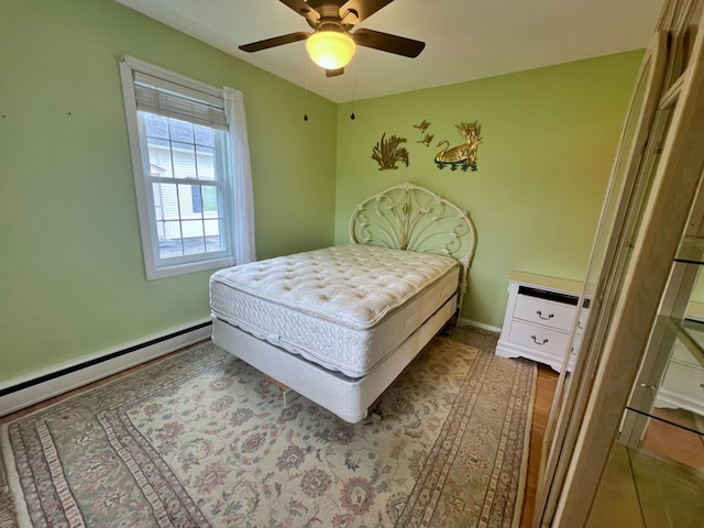 bedroom with baseboard heating, ceiling fan, and hardwood / wood-style flooring