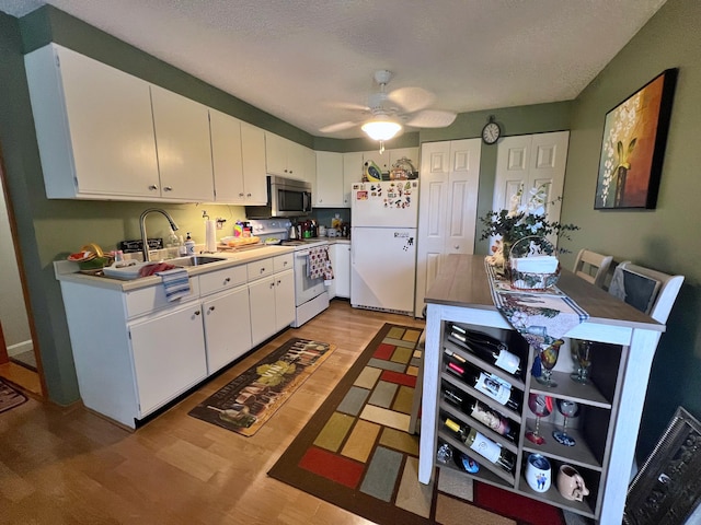 kitchen featuring hardwood / wood-style flooring, white appliances, sink, and white cabinets