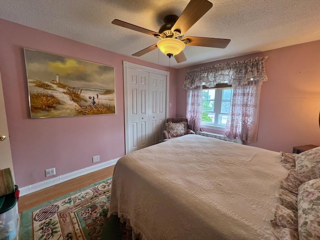 bedroom featuring ceiling fan, hardwood / wood-style flooring, a closet, and a textured ceiling