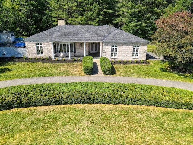 ranch-style home featuring a chimney and a front lawn