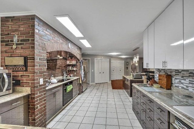 kitchen featuring decorative light fixtures, stainless steel appliances, light stone countertops, light tile patterned floors, and white cabinetry