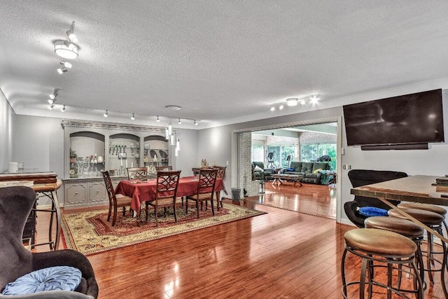 dining room with wood-type flooring, a textured ceiling, and track lighting