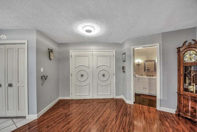 interior space featuring ensuite bath, hardwood / wood-style flooring, and a textured ceiling