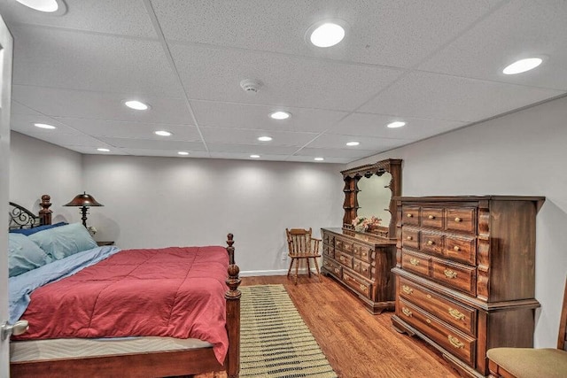 bedroom with a paneled ceiling and light hardwood / wood-style flooring