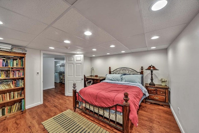 bedroom with baseboards, wood finished floors, recessed lighting, and a drop ceiling