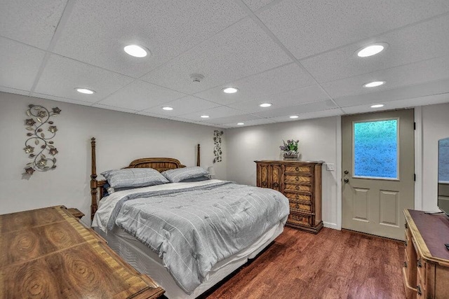 bedroom with a paneled ceiling and dark hardwood / wood-style flooring