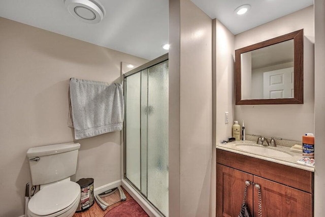 bathroom with walk in shower, hardwood / wood-style flooring, vanity, and toilet