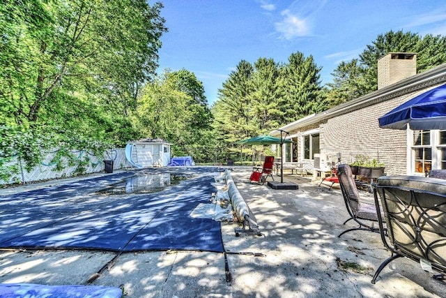 view of patio / terrace featuring a covered pool and a shed