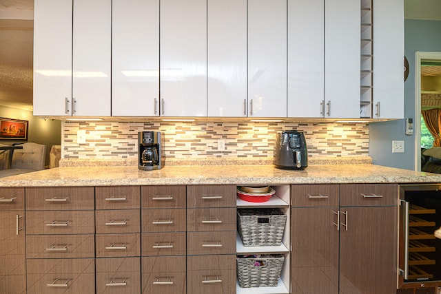 kitchen with light stone countertops, white cabinets, and wine cooler