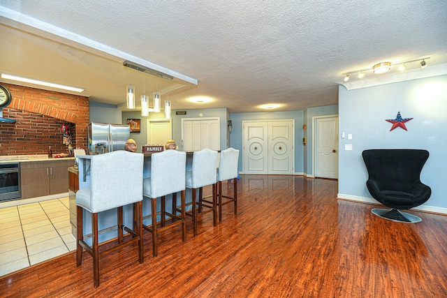 kitchen featuring a kitchen island, stainless steel appliances, a breakfast bar, light hardwood / wood-style flooring, and a textured ceiling