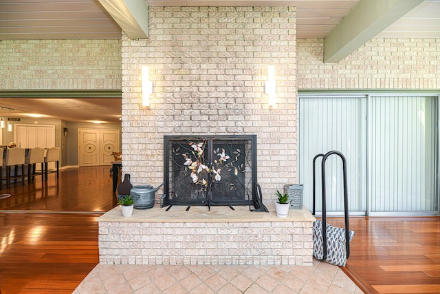 room details with wood-type flooring, beam ceiling, and a brick fireplace