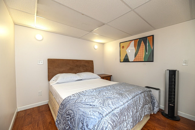 bedroom with a paneled ceiling and dark wood-type flooring