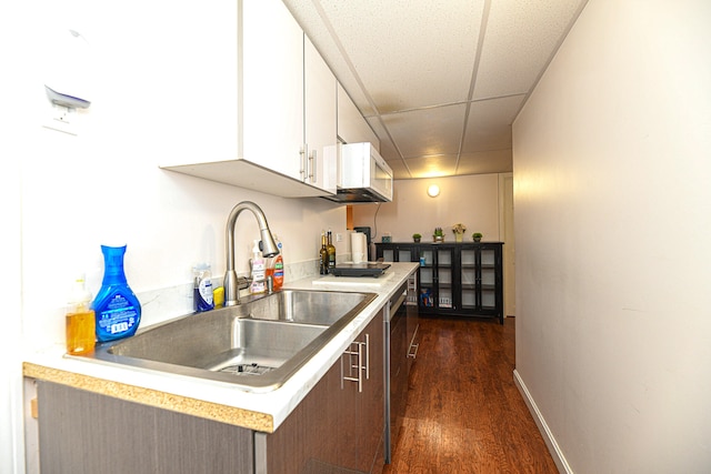 kitchen with a drop ceiling, dark hardwood / wood-style flooring, sink, stainless steel dishwasher, and white cabinetry