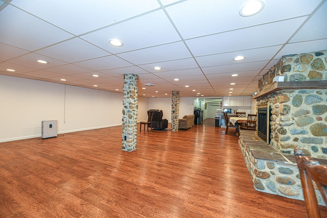 exercise area with a drop ceiling, decorative columns, a fireplace, and hardwood / wood-style floors