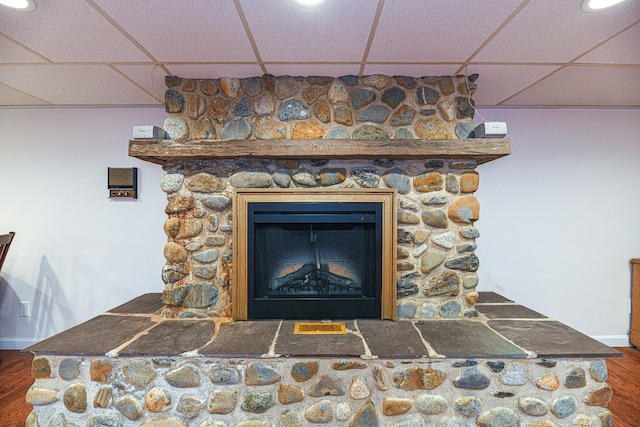 interior details with a fireplace, a paneled ceiling, and wood-type flooring