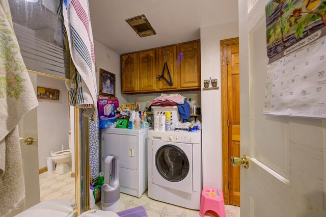 clothes washing area featuring independent washer and dryer and cabinets