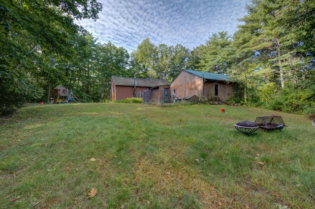 view of yard featuring a playground and an outdoor fire pit