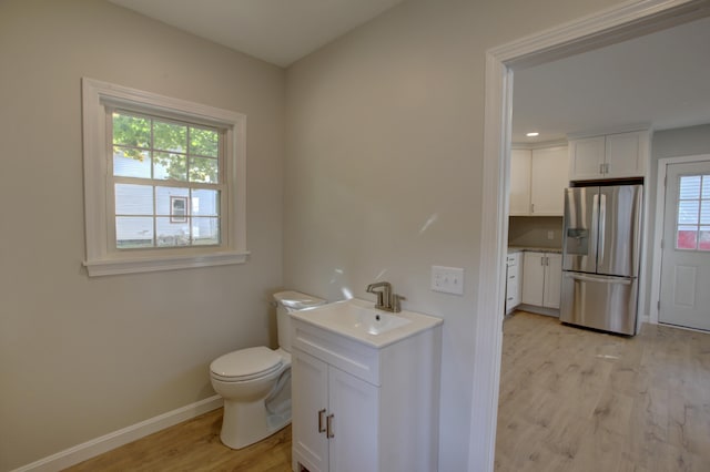 bathroom featuring hardwood / wood-style flooring, vanity, toilet, and a wealth of natural light