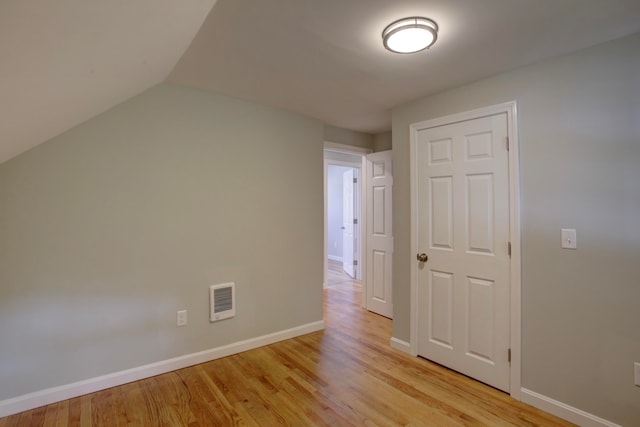 additional living space featuring light wood-type flooring and vaulted ceiling