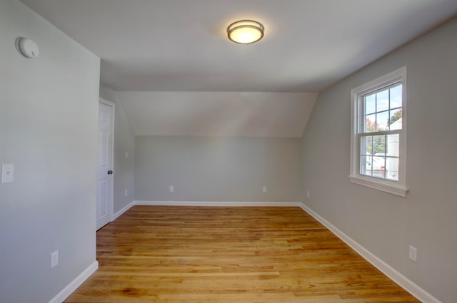 additional living space featuring lofted ceiling and light hardwood / wood-style flooring