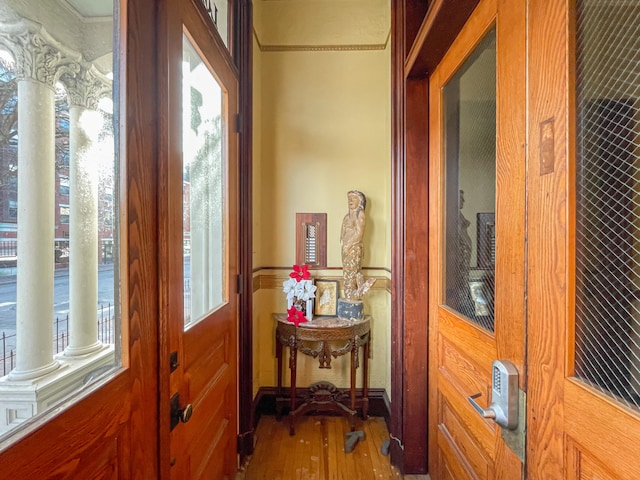 foyer entrance with hardwood / wood-style flooring, ornate columns, and a wealth of natural light