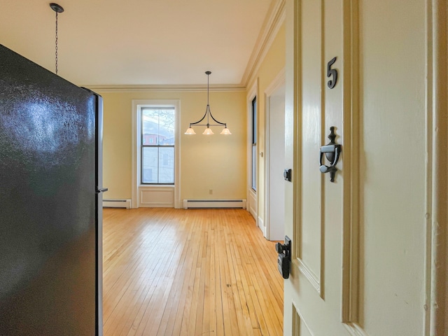 unfurnished dining area with light wood-type flooring, crown molding, and a baseboard heating unit