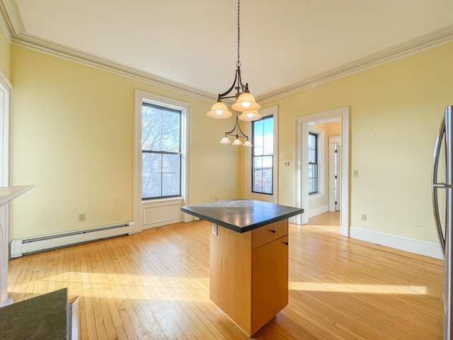 kitchen with pendant lighting, crown molding, a baseboard heating unit, and light wood-type flooring