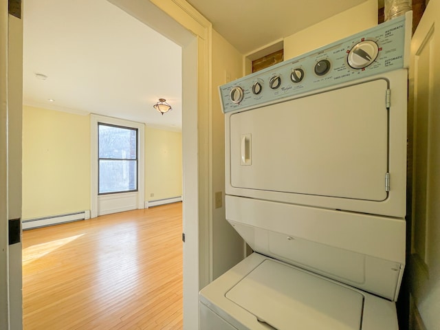 washroom featuring light wood-type flooring, a baseboard radiator, and stacked washing maching and dryer