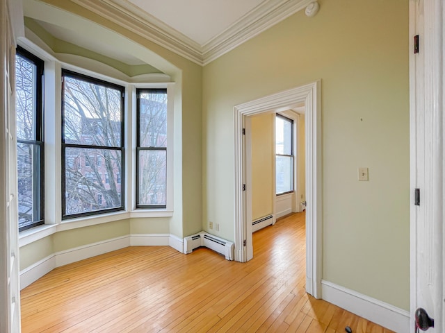 empty room with ornamental molding, light wood-type flooring, and a baseboard radiator