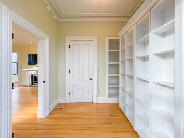 hall with crown molding and light hardwood / wood-style flooring