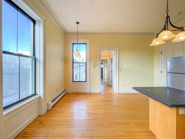 unfurnished dining area with an inviting chandelier, light hardwood / wood-style floors, crown molding, and a baseboard heating unit