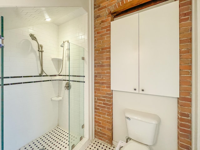 bathroom featuring a shower with door, toilet, and brick wall