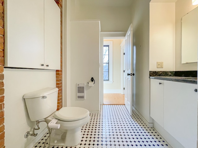 bathroom featuring vanity, heating unit, and toilet