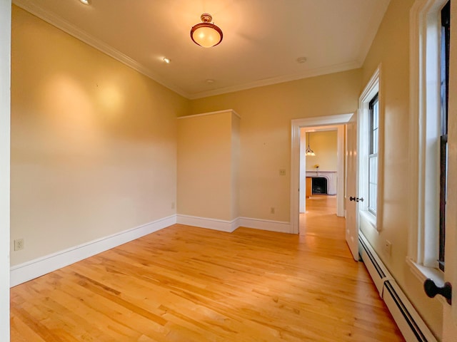 empty room featuring ornamental molding, light hardwood / wood-style flooring, and baseboard heating