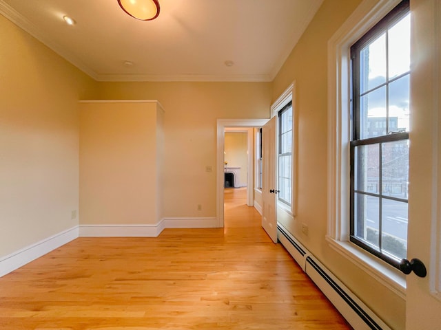 corridor with crown molding, a baseboard heating unit, and light hardwood / wood-style floors