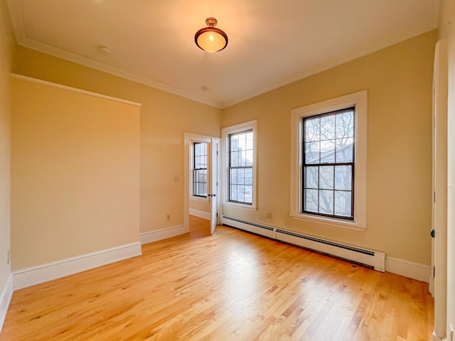 empty room with light hardwood / wood-style flooring, crown molding, and a baseboard heating unit