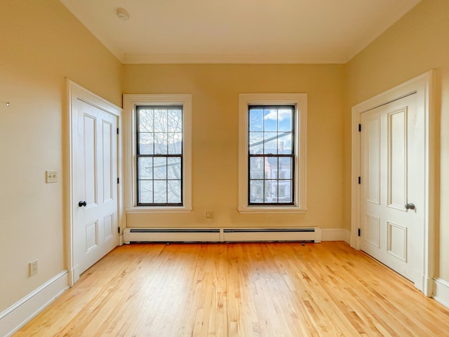 entrance foyer with baseboard heating, plenty of natural light, and light hardwood / wood-style floors