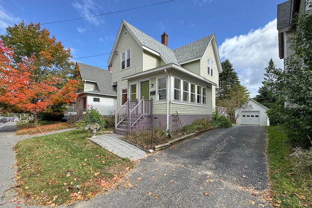 view of front of home featuring a garage, a front lawn, and an outbuilding