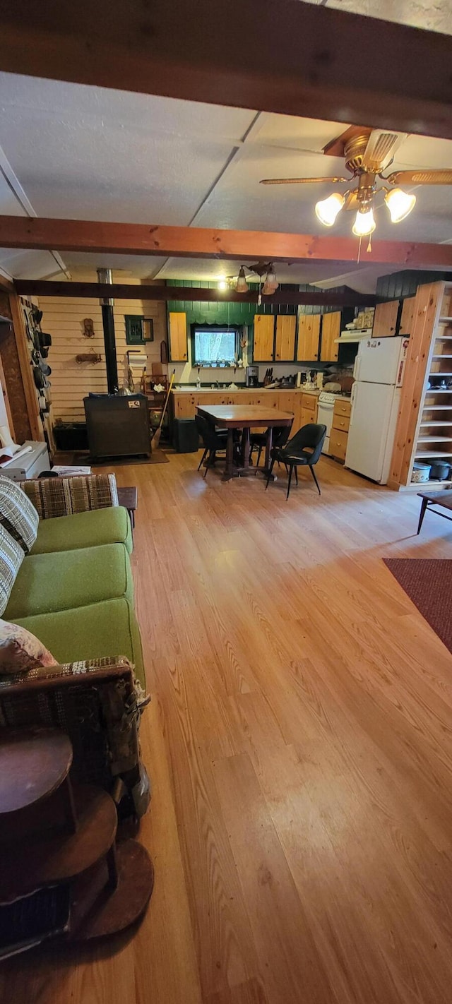 living room featuring beam ceiling, ceiling fan, and light hardwood / wood-style flooring