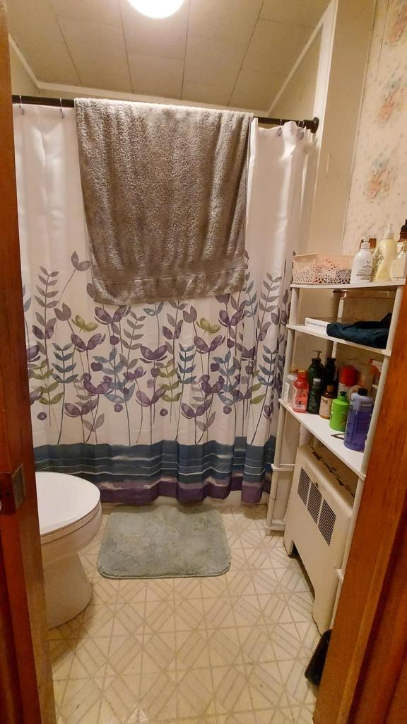 60 Elm St, East Millinocket, ME 04430 - full bathroom featuring tile patterned floors, a shower with shower curtain, and radiator heating unit